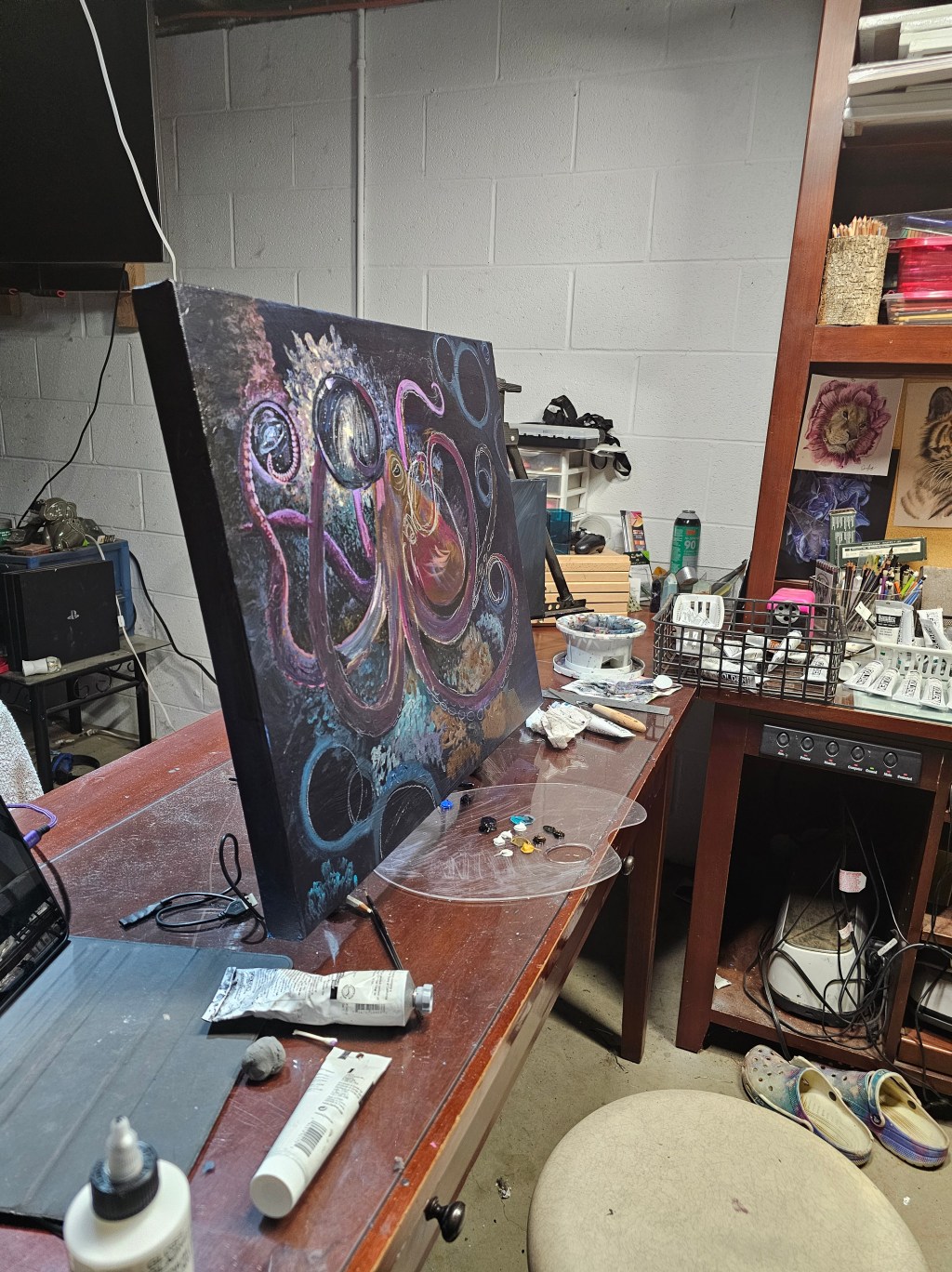 Studio photograph of a colorful octopus-inspired painting on an easel with art supplies nearby.