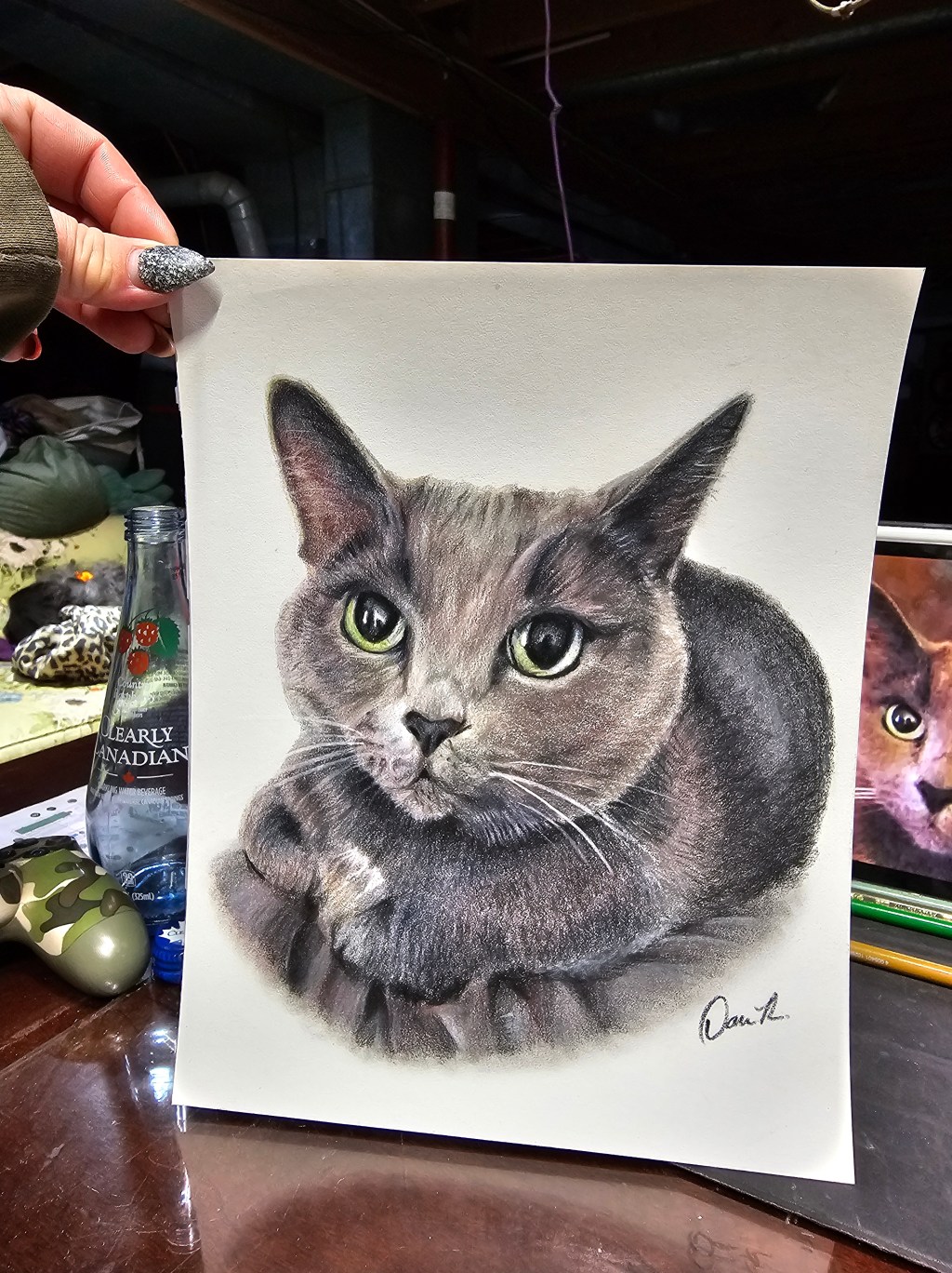 Seated gray cat portrait with striking green eyes and delicate fur detail.